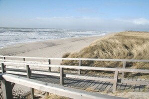 A wooden boardwalk leading to a sandy beach with dunes in the background. - Holiday apartment with 3 bedrooms (Hörnum \/ Sylt)