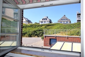 A view from a window with a clear sky, a parking lot, and buildings with sloped roofs. - Holiday apartment with 3 bedrooms (Hörnum \/ Sylt)