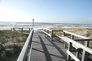 A wooden boardwalk leading to the ocean with a clear sky. - Holiday apartment with 3 bedrooms (Hörnum \/ Sylt)
