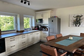 Eine moderne Küche mit weißen Schränken, einem Edelstahl-Kühlschrank und einem Essbereich mit Holztisch und Stühlen.