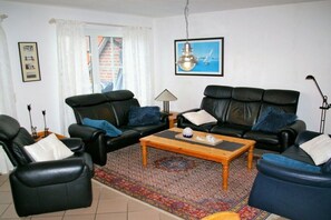 A living room with two black leather sofas, a wooden coffee table, and a patterned rug. - Holiday home with 4 bedrooms (Carolinensiel)