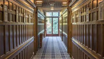 A corridor with wooden paneling and a checkered floor leading to a glass door.
