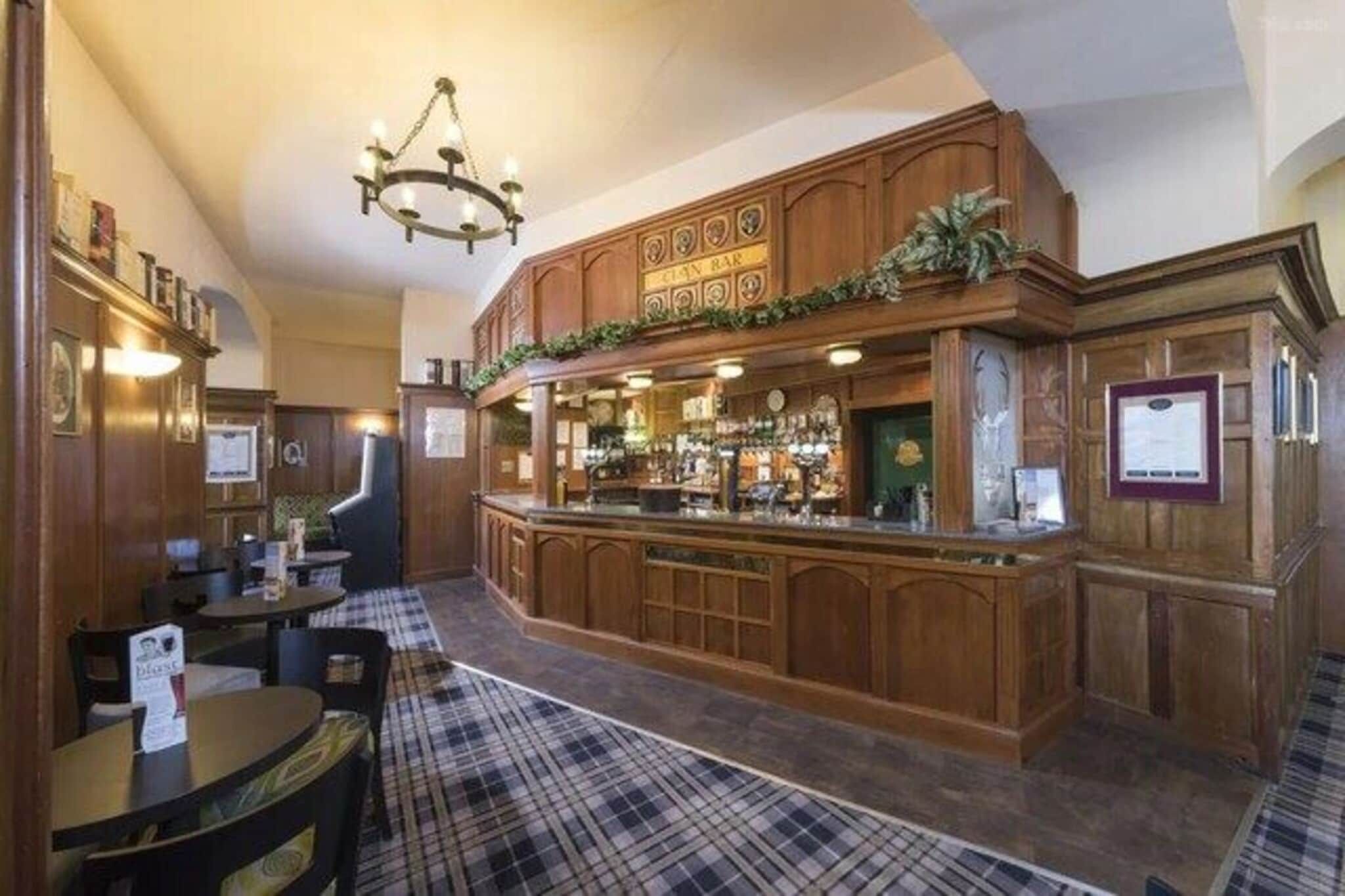 A bar area with wooden furnishings, a checkered floor, and a chandelier.