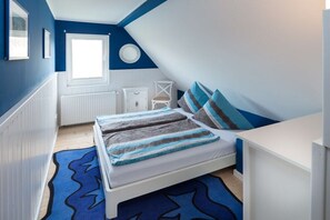 Ein Schlafzimmer mit einem Bett, einem Fenster, einem Heizkörper und einem weißen Schrank.
