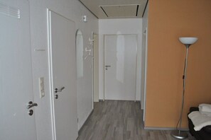 A hotel hallway with a wooden floor, white doors, and a floor lamp. - Holiday apartment with 1 bedroom (Greetsiel)