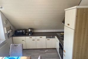 Eine kleine Küche mit einer Mikrowelle, einer Kaffeemaschine und einem Spülbecken.
