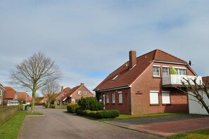 A residential street with houses, a clear sky, and a paved road. - Holiday apartment with 1 bedroom (Greetsiel)