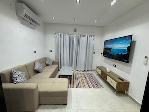 A modern living room with a sofa, a coffee table, a TV, and a patterned rug. - Your Perfect Getaway in Naama Bay, Sharm El Sheikh! (South Sinai Governorate)