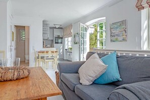 Ein modernes Wohnzimmer mit einem grauen Sofa, einem Holztisch und einer Küche im Hintergrund.