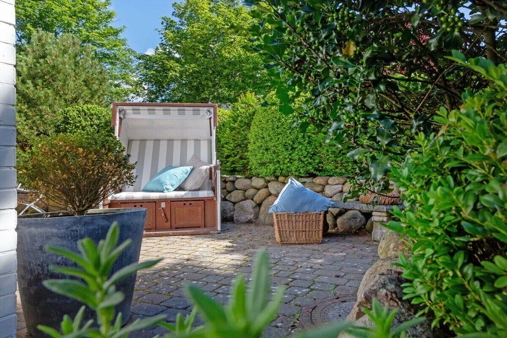 A patio with a cushioned seating area, a stone wall, and a potted plant.