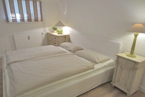 Ein Schlafzimmer mit einem Doppelbett, Nachttischen, einer Lampe und einem Heizkörper.