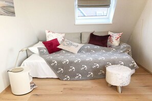 A small, cozy bedroom with a bed, pillows, a bedside table, a lamp, and a window. - Holiday apartment with 2 bedrooms (Hörnum)