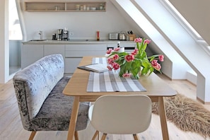 Une cuisine moderne avec un coin repas comprenant un banc, une table avec un set de table et une chaise.