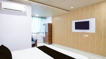 A hotel room with a bed, a TV mounted on the wall, and a wooden panel wall.