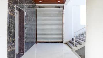A hallway with a closed roller door, a staircase, and a marble wall.