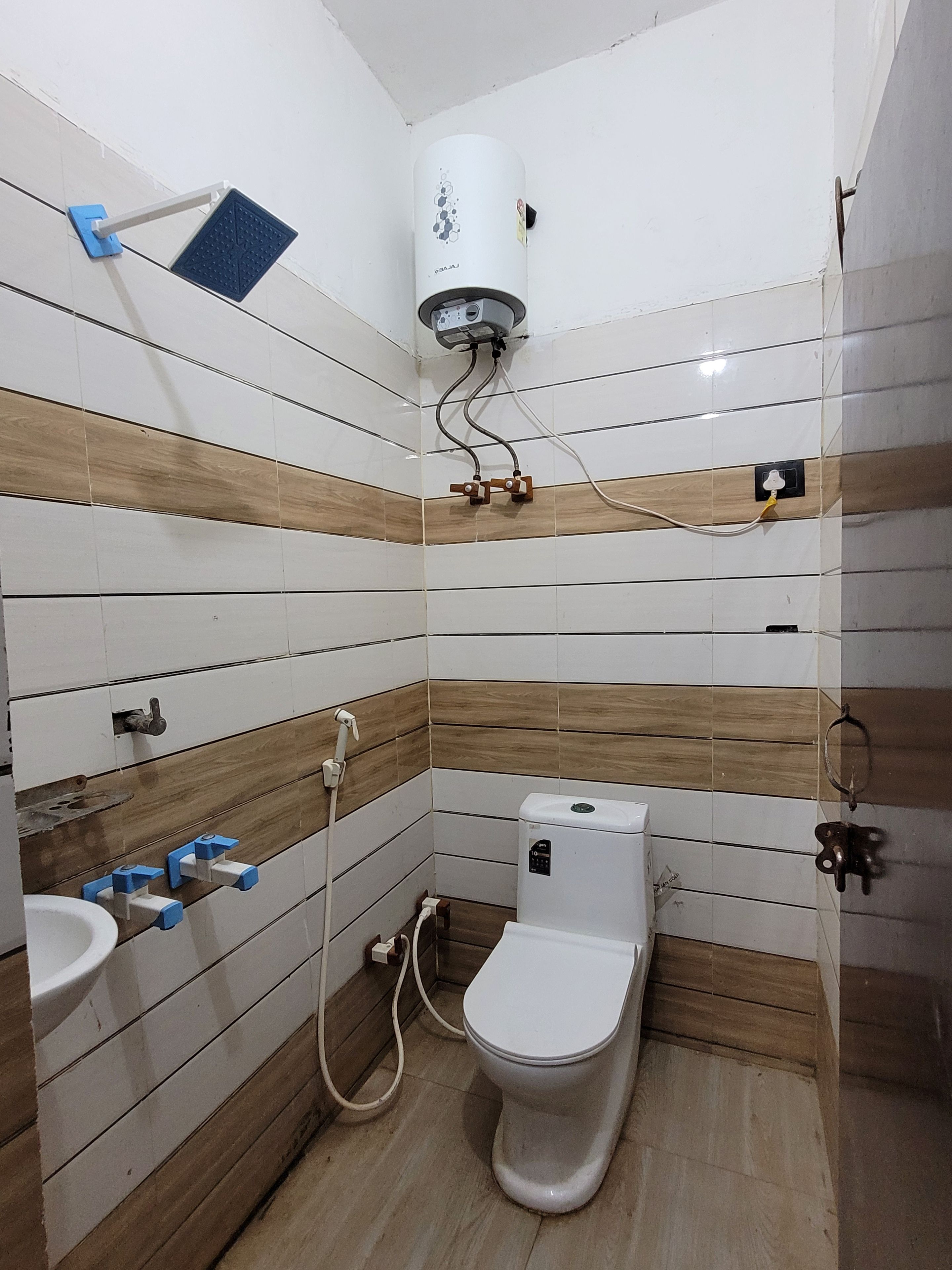 A bathroom with a toilet, sink, and a water heater mounted on the wall.