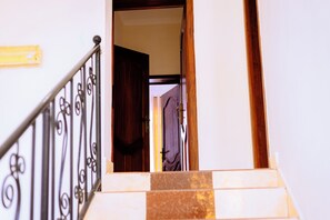 Un escalier avec une rampe en métal et une porte en bois donnant sur une autre pièce.