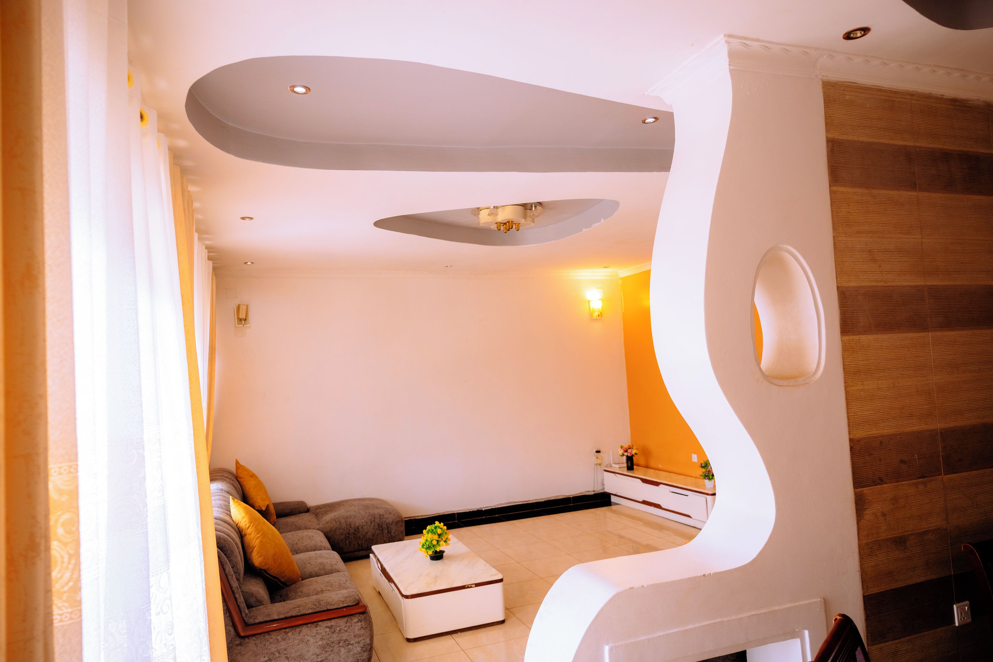A modern living room with a sofa, a coffee table, and a unique architectural feature.