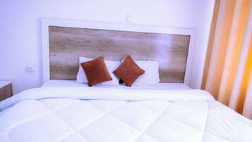 Una cama con cabecera de madera, ropa de cama blanca y dos almohadas marrones.