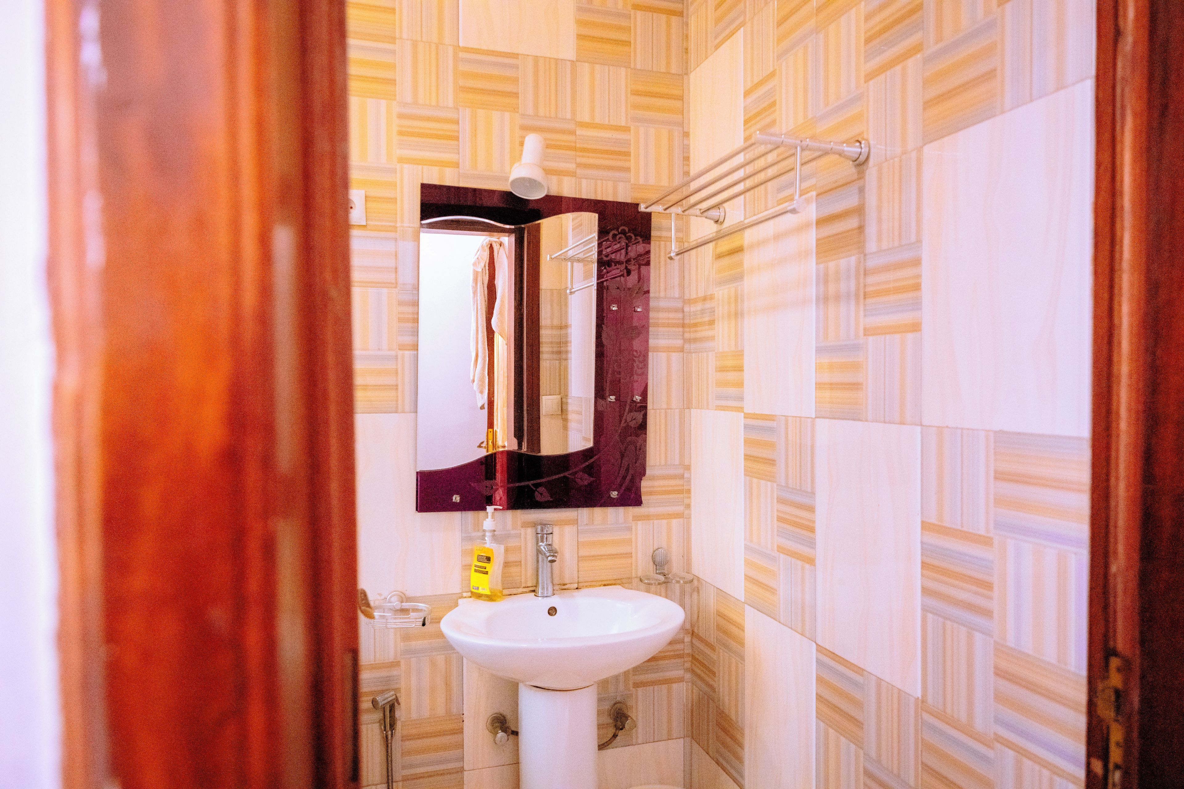 Un bagno con un lavandino bianco, uno specchio e piastrelle decorate.