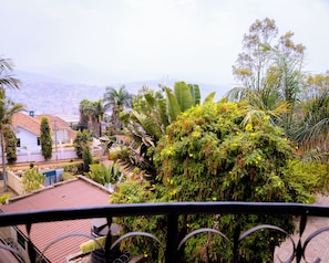 Zona residencial con casas, un balcón y vistas a un paisaje urbano en la distancia.