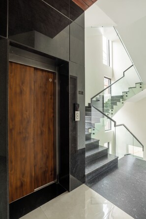 Ein modernes Interieur mit einer Holztür, einer Treppe mit Glastrennstäben und einem klaren, minimalistischen Design.
