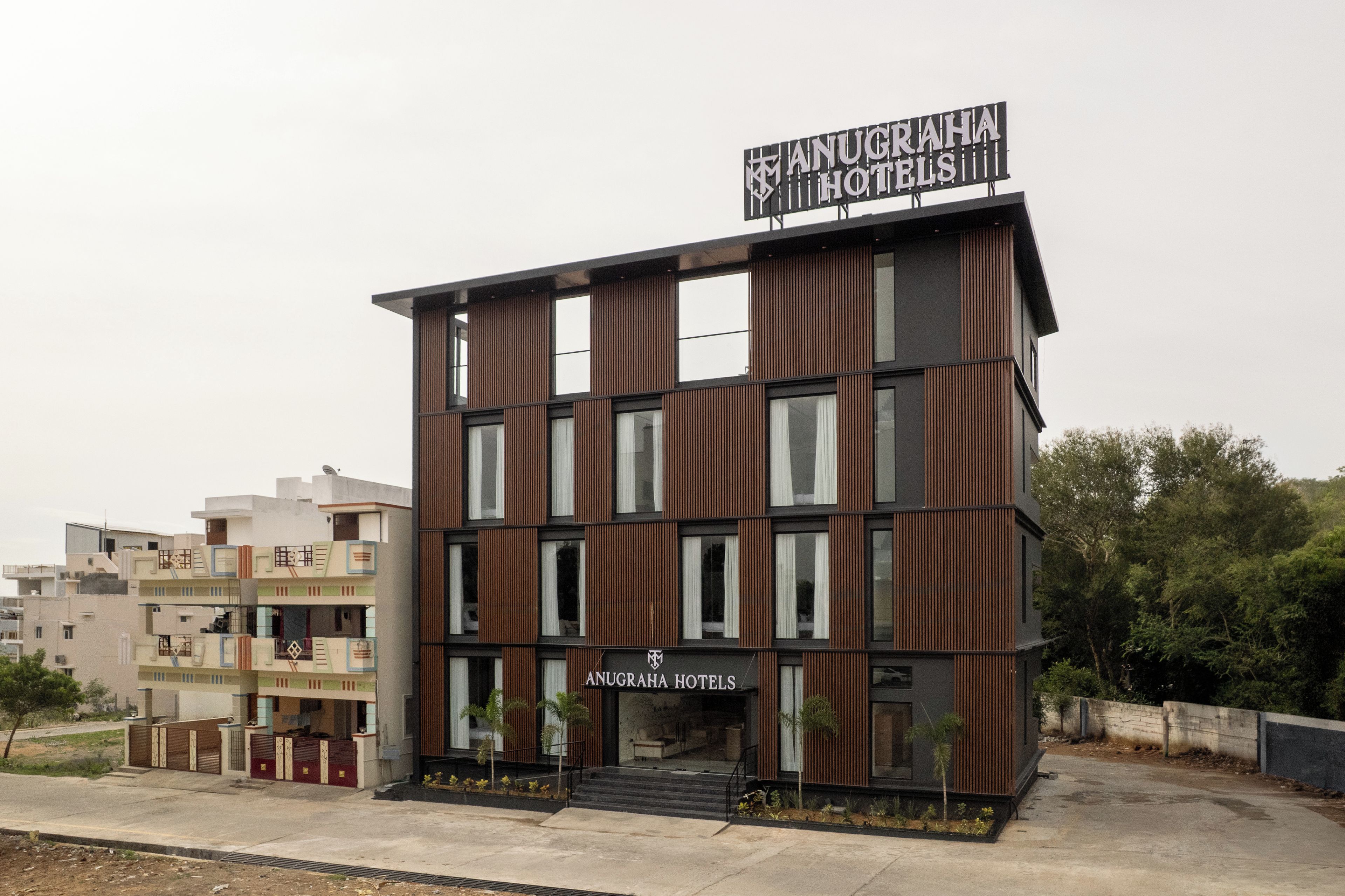Un moderno edificio de hotel con un letrero llamativo que dice 'ANUGRAHA HOTELS'.