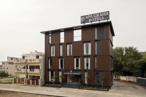 Un edificio moderno di un hotel con un cartello ben visibile che riporta 'ANUGRAHA HOTELS'.