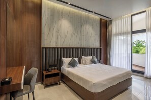 Moderni hotellihuone, jossa on suuri sänky, työpöytä ja tuoli.