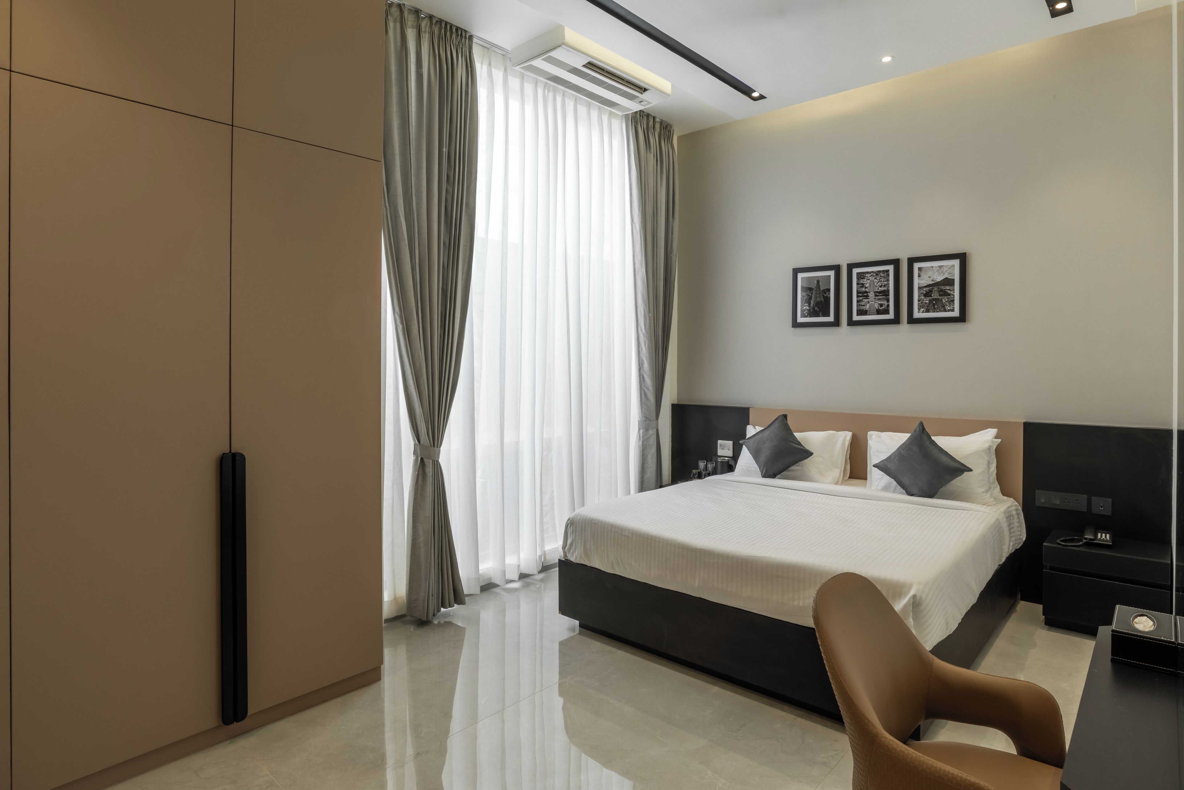 Una habitación de hotel moderna con una cama grande, un escritorio y una silla. Hay tres cuadros en la pared.