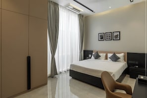 Una habitación de hotel moderna con una cama grande, un escritorio y una silla. Hay tres cuadros en la pared.