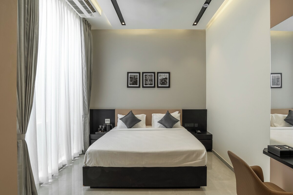 Camera d'albergo moderna con un ampio letto, comodini, una scrivania e una sedia. Tre quadri appesi alla parete.