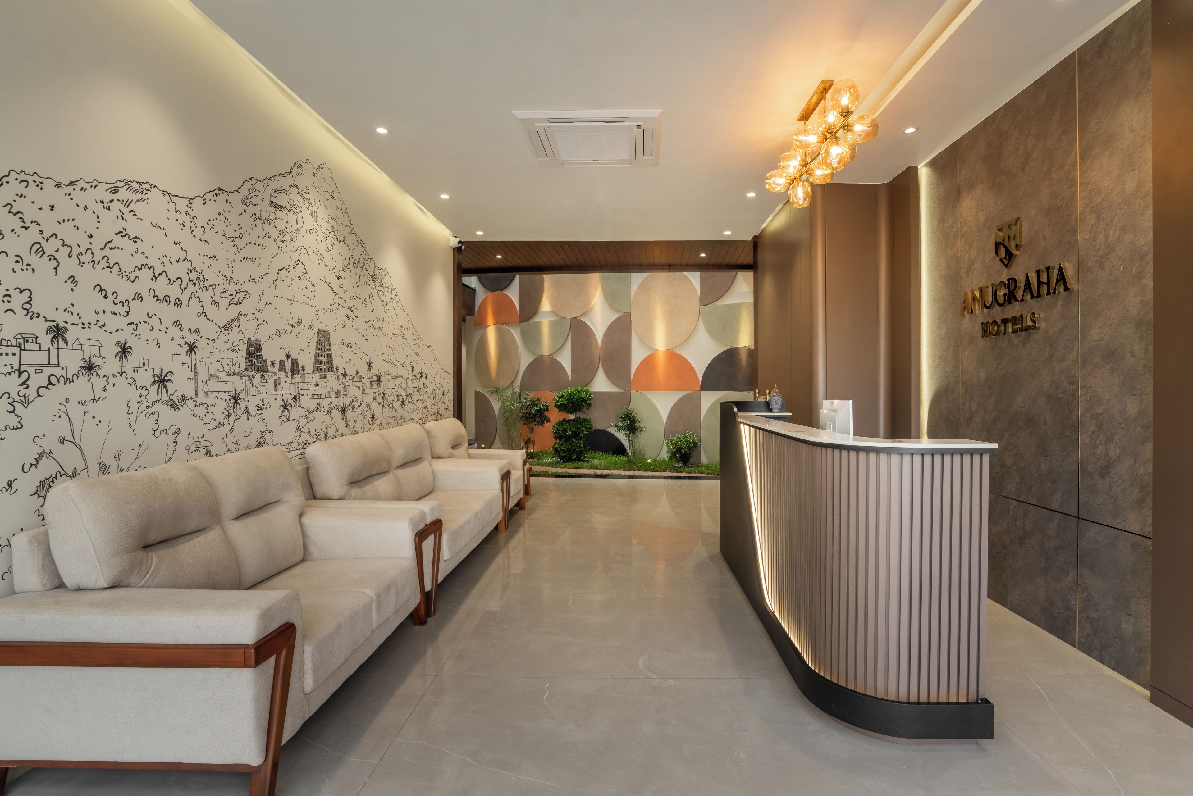 Zona de recepción de hotel con diseño moderno, que incluye mostrador de recepción, área de estar y decoración mural.