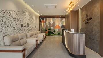 Zona de recepción de hotel con diseño moderno, que incluye mostrador de recepción, área de estar y decoración mural.