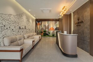 Una zona reception di un hotel dal design moderno, con scrivania, salottino e opere d'arte decorative a parete.