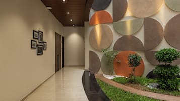 Un pasillo moderno con piso pulido, una serie de decoraciones circulares en la pared y un pequeño jardín con plantas y un borde de madera.