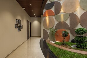 Un corridoio moderno con pavimento lucido, diverse decorazioni circolari a parete e una piccola area giardino con piante e bordura in legno.