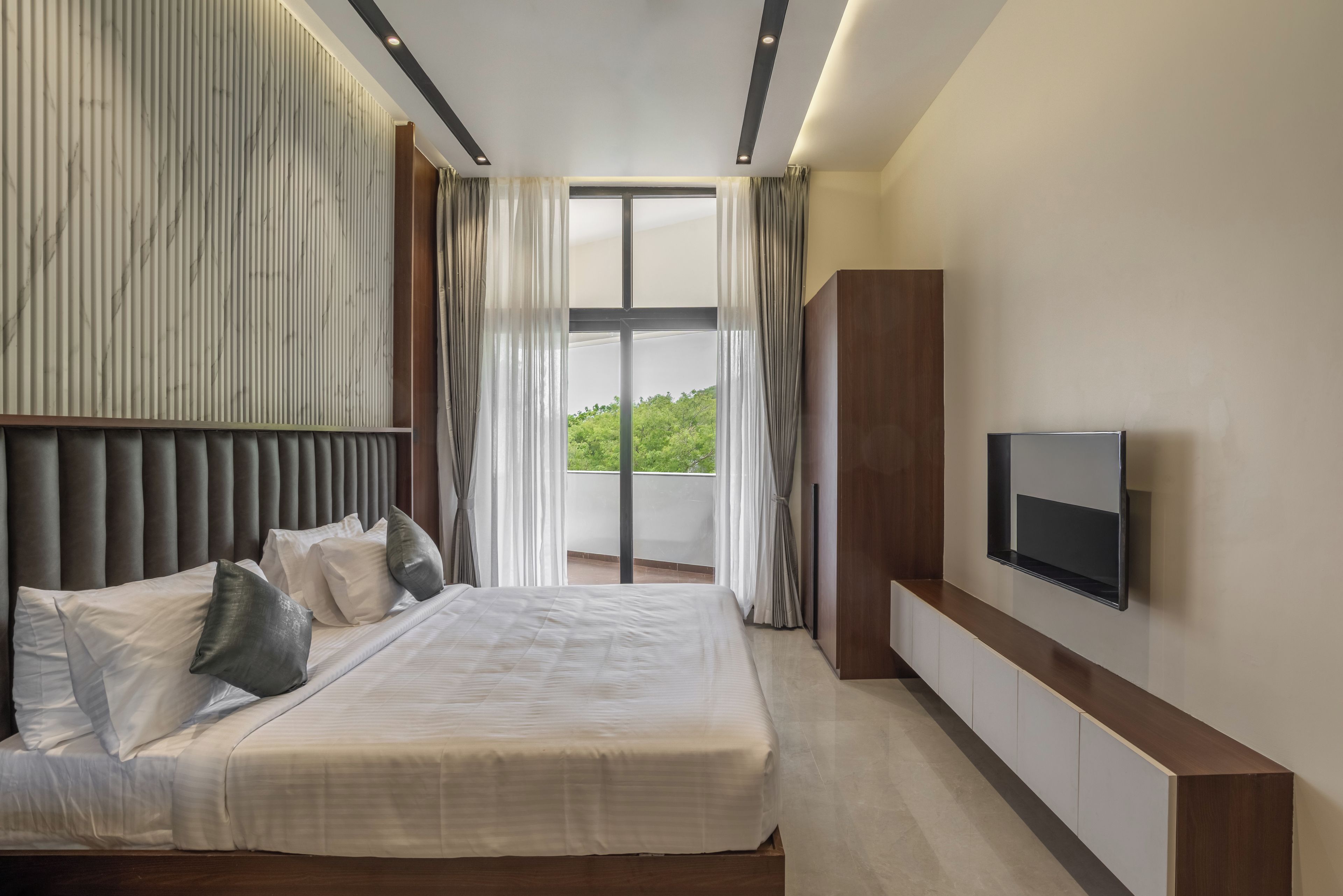 Un dormitorio moderno con una cama grande, un televisor de pantalla plana y vistas a zonas verdes.