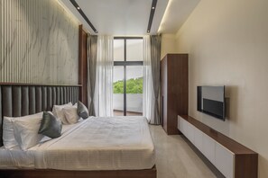 Una camera da letto moderna con un letto grande, una TV a schermo piatto e vista sul verde circostante.
