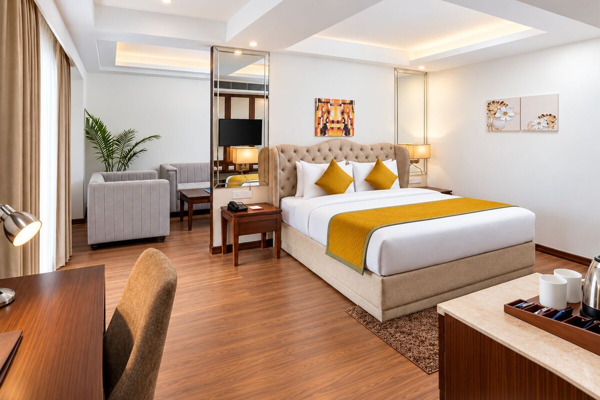 Une chambre d’hôtel équipée d’un lit, d’un bureau, d’une chaise, d’un canapé, d’une télévision et d’une plante.