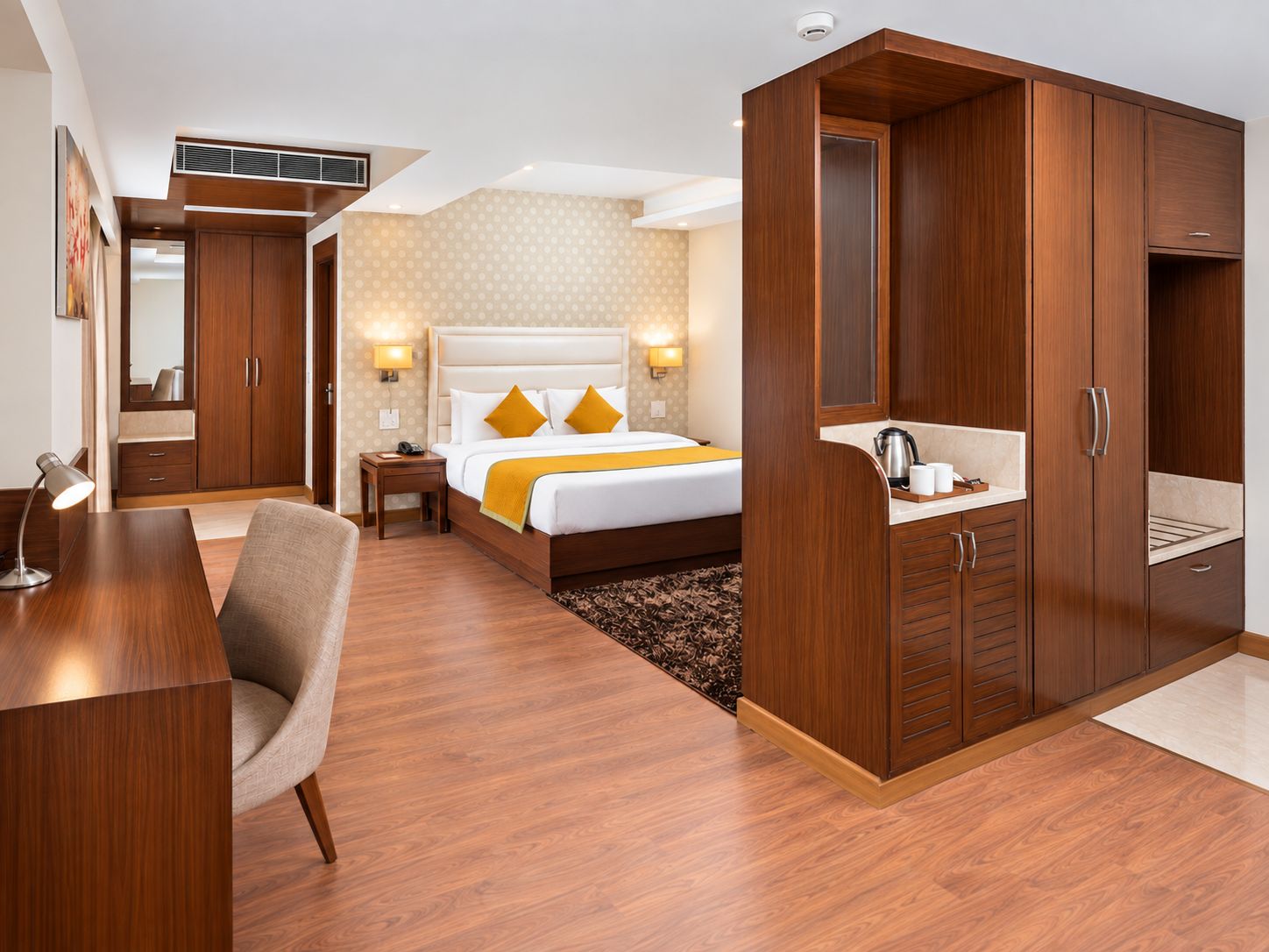 Una habitación de hotel con cama, escritorio, armario y kitchenette.