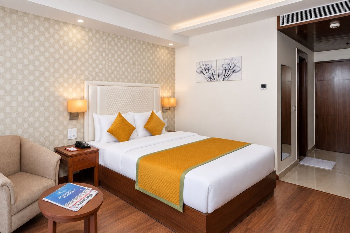 Une chambre d’hôtel avec un lit, une table de chevet, une lampe et une chaise.
