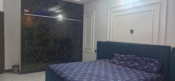 A bedroom with a bed, a wardrobe, and a door.