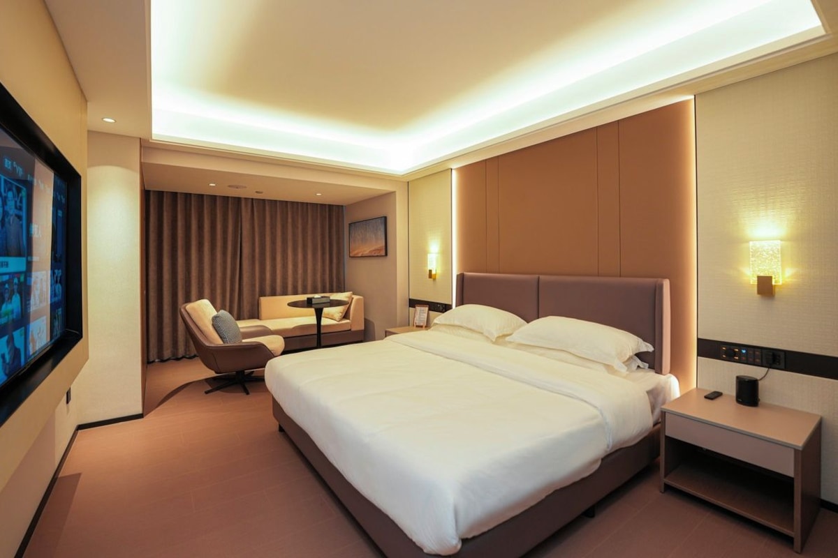 Habitación de hotel con una cama grande, un escritorio, una silla y un televisor en la pared.