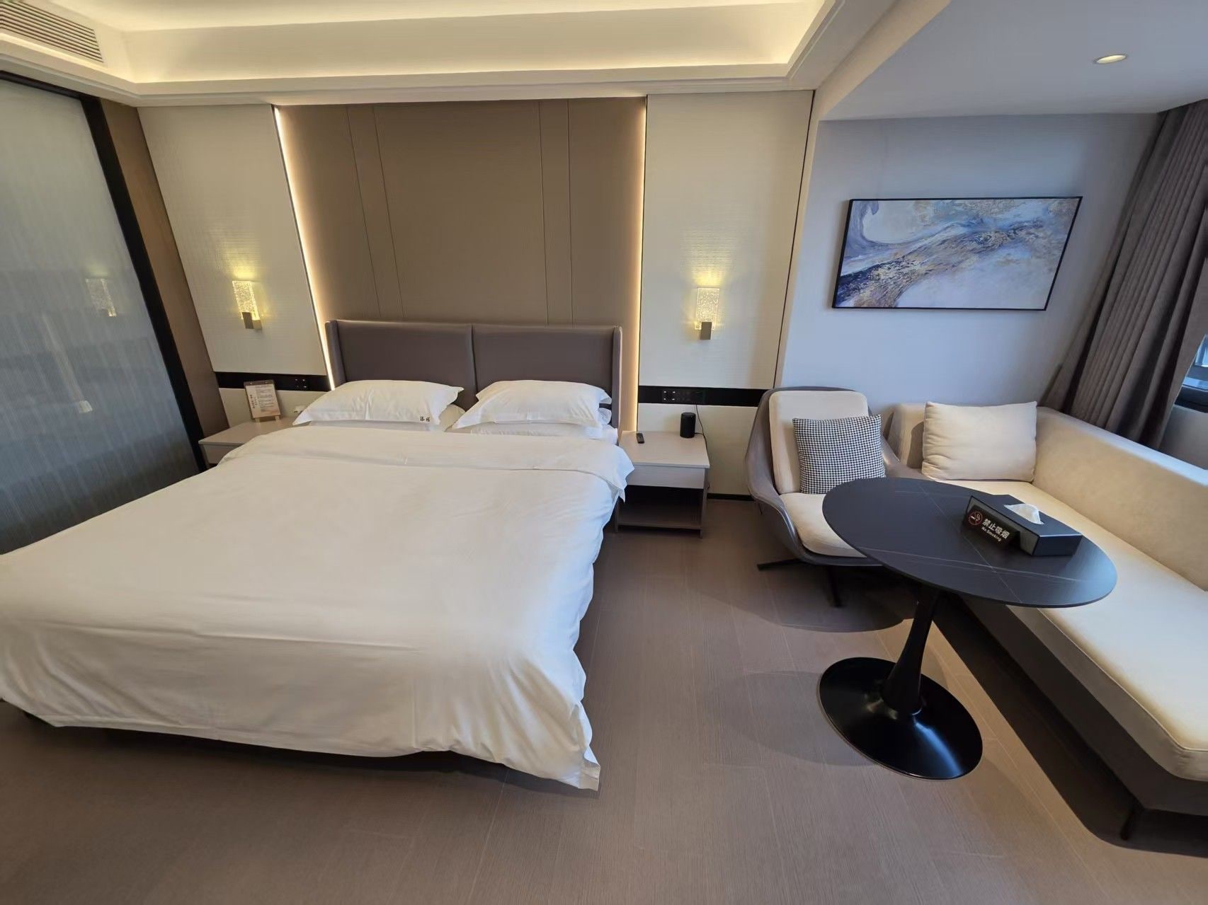 Ett modernt hotellrum med en stor säng, en soffa, ett litet bord och en tavla på väggen.