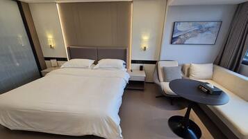 Ett modernt hotellrum med en stor säng, en soffa, ett litet bord och en tavla på väggen.