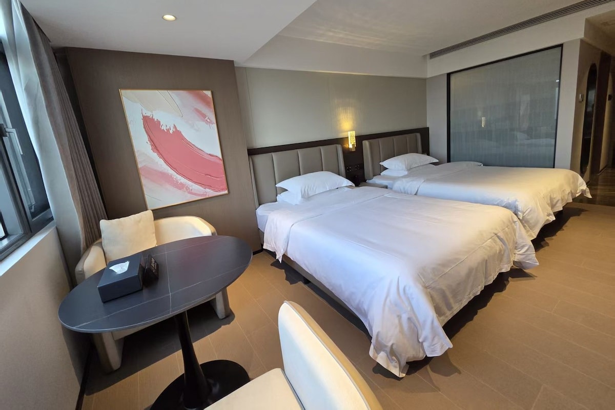 Habitación de hotel con dos camas, un escritorio y una silla.