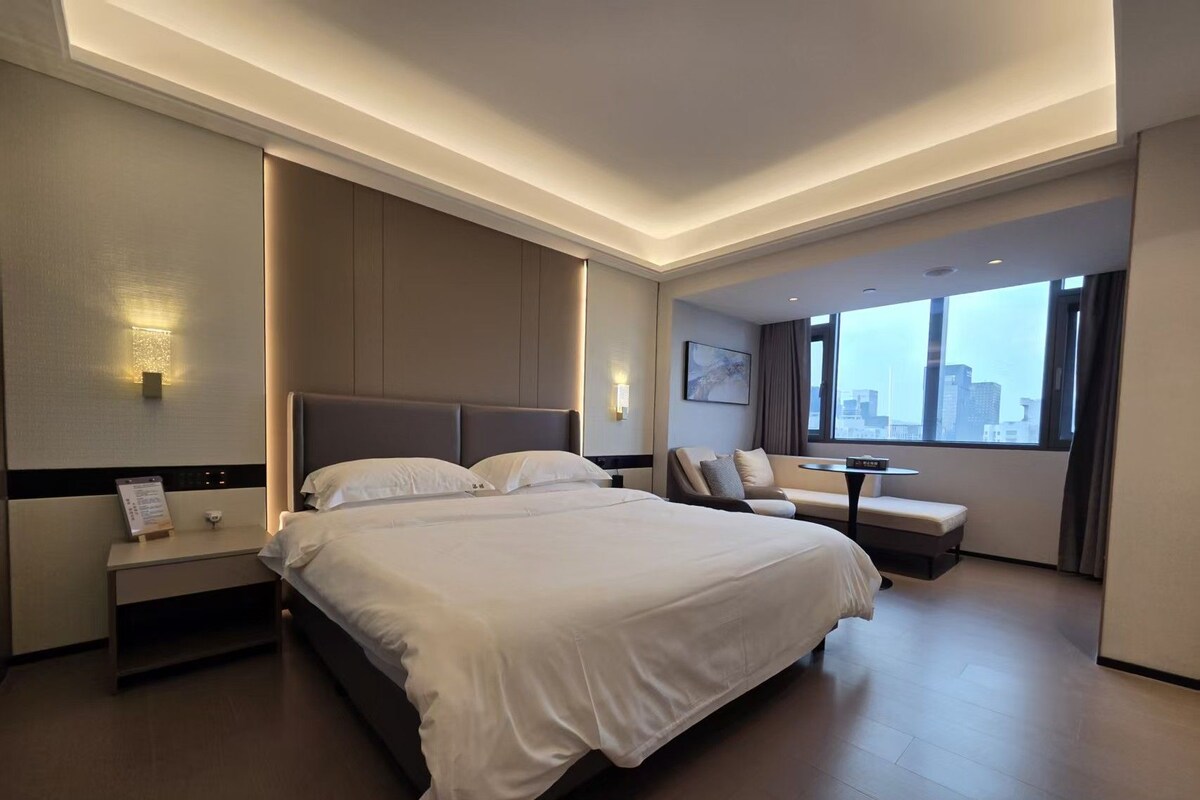 Habitación de hotel moderna con una cama grande, un escritorio y vistas a la ciudad.