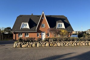 A two-story house with a stone wall in front, a brick facade, and a sloped roof. - at the Arnfried country house (Wenningstedt)