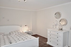 A bedroom with a bed, a nightstand, a dresser, and a wall-mounted mirror. - at the Arnfried country house (Wenningstedt)